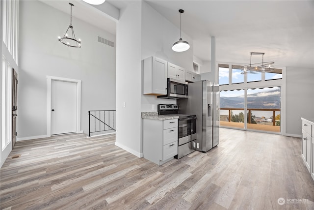 kitchen featuring high vaulted ceiling, light hardwood / wood-style flooring, appliances with stainless steel finishes, and white cabinets