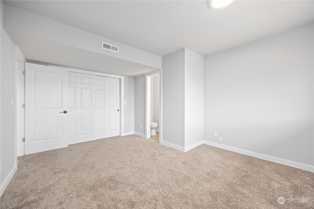 unfurnished bedroom with carpet flooring, ensuite bath, and a closet