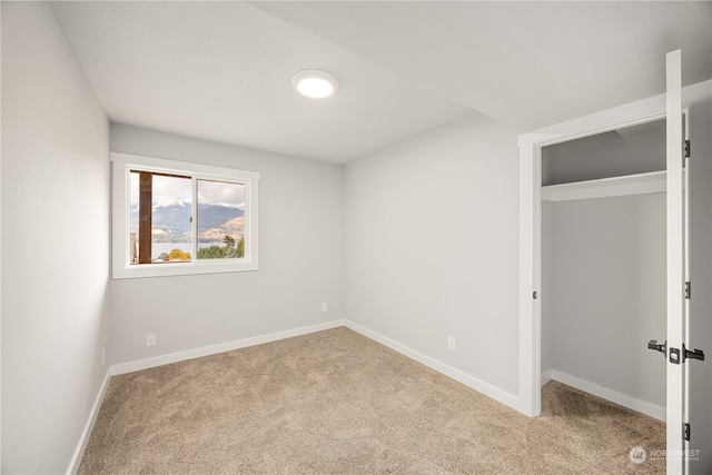 unfurnished bedroom with a closet and light colored carpet