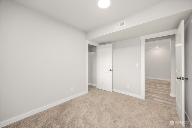 unfurnished bedroom featuring light carpet and a closet