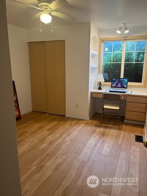 office area with ceiling fan, built in desk, and light hardwood / wood-style floors