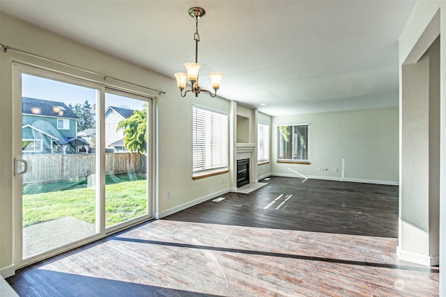 unfurnished living room with dark hardwood / wood-style floors and a chandelier