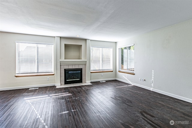 unfurnished living room with a fireplace, a textured ceiling, and dark hardwood / wood-style flooring