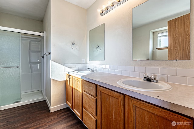 bathroom with wood-type flooring, tasteful backsplash, vanity, and a shower with shower door