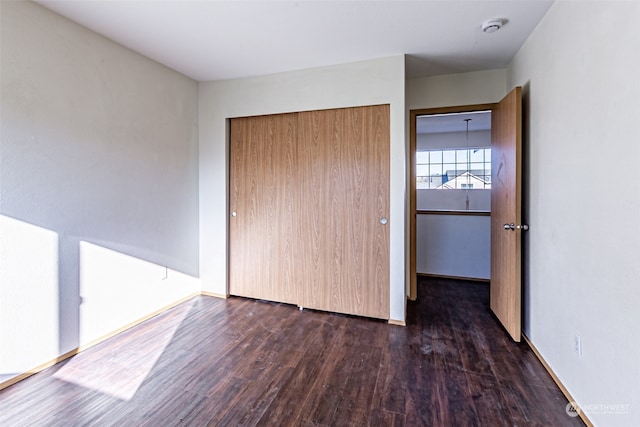 unfurnished bedroom with a closet and dark hardwood / wood-style floors