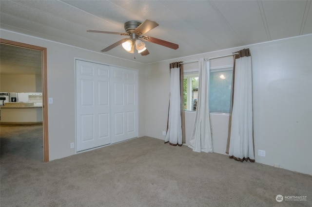 unfurnished bedroom with light carpet, ceiling fan, and a closet