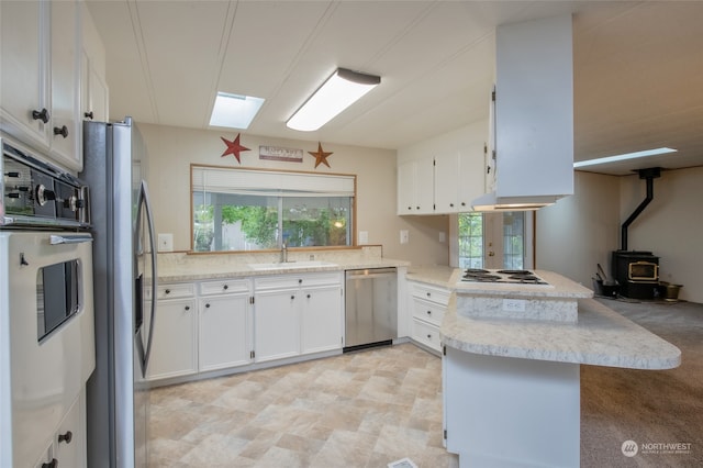 kitchen with appliances with stainless steel finishes, white cabinetry, plenty of natural light, and kitchen peninsula