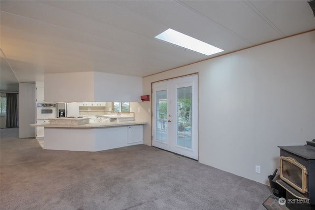 unfurnished living room featuring sink, french doors, light carpet, and a wood stove