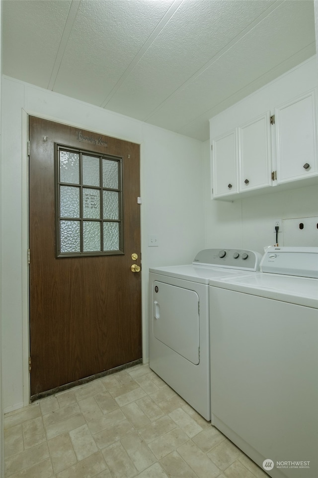 clothes washing area with cabinets, a textured ceiling, and washing machine and clothes dryer