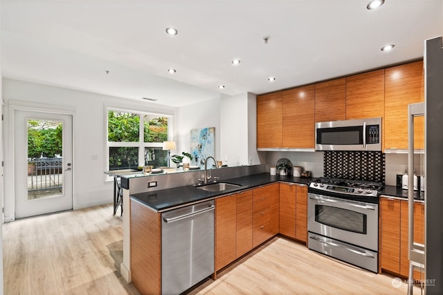 kitchen featuring kitchen peninsula, stainless steel appliances, light hardwood / wood-style flooring, and sink