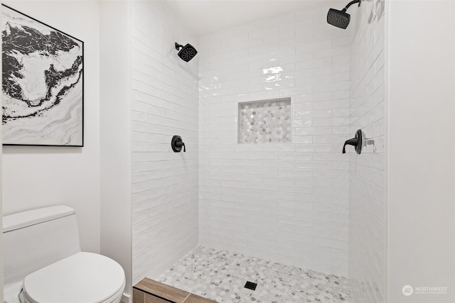 bathroom featuring tiled shower and toilet