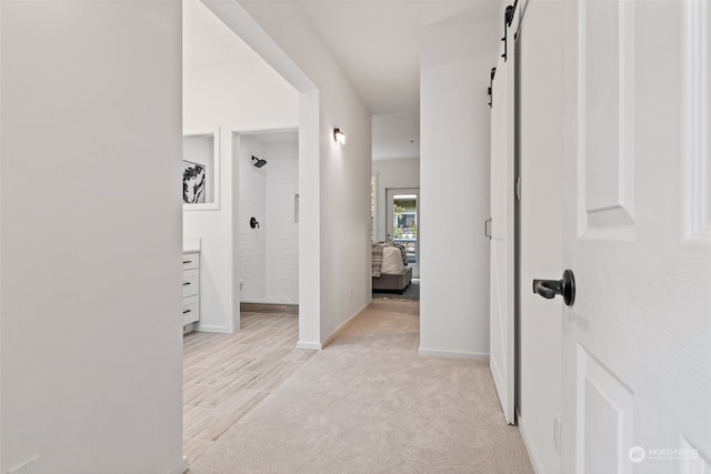 corridor with a barn door and light colored carpet