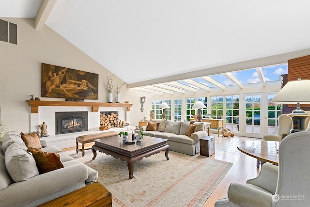 living room with french doors, a tile fireplace, beam ceiling, high vaulted ceiling, and light hardwood / wood-style floors