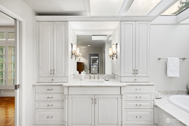 bathroom featuring vanity, a bath, and parquet flooring