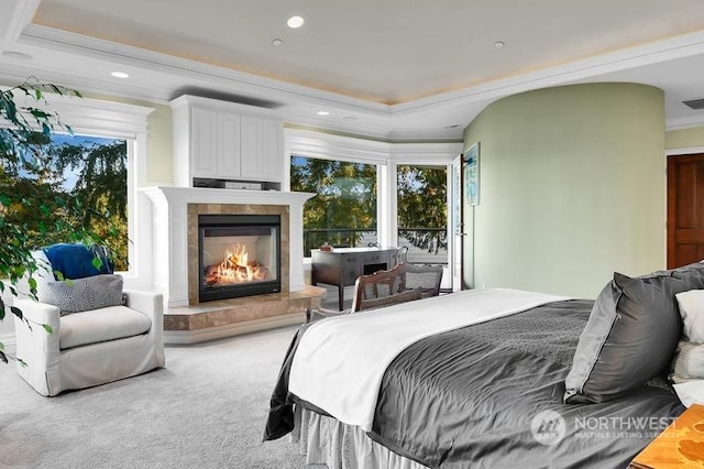 bedroom featuring a tile fireplace, a tray ceiling, carpet flooring, and ornamental molding