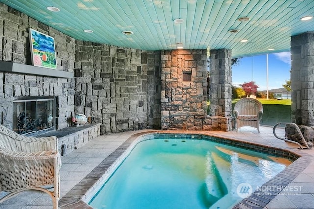 view of pool featuring a patio area and an outdoor stone fireplace