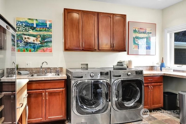 clothes washing area with washer and clothes dryer, cabinets, and sink