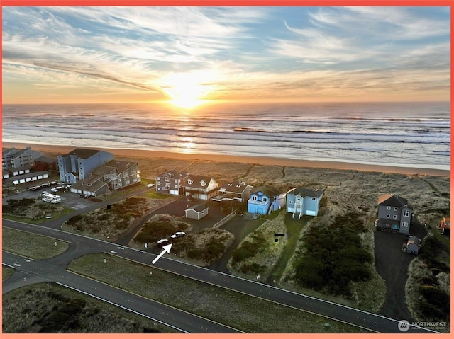 aerial view at dusk with a water view and a beach view