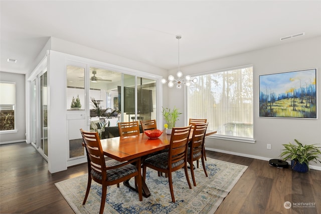 dining area with ceiling fan with notable chandelier, a wealth of natural light, and dark hardwood / wood-style flooring