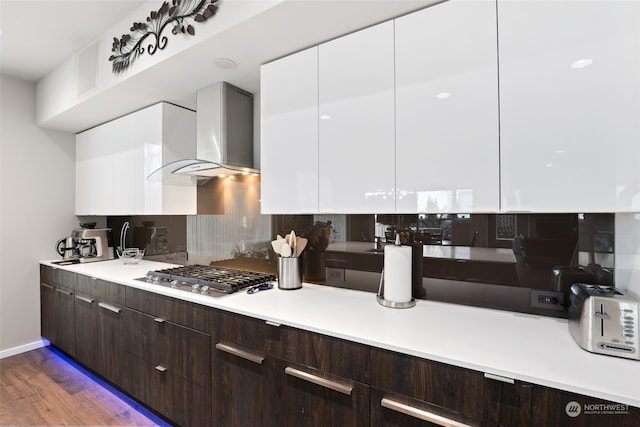 kitchen featuring dark wood-type flooring, white cabinetry, and wall chimney exhaust hood