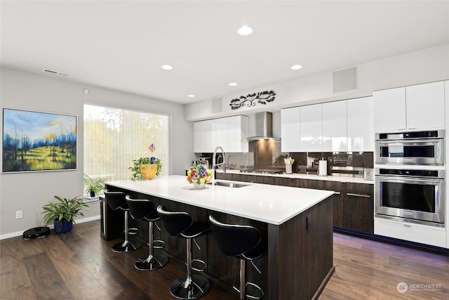 kitchen with a kitchen breakfast bar, dark hardwood / wood-style floors, a center island with sink, and sink