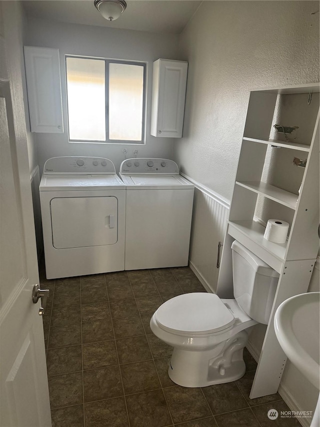 bathroom featuring tile patterned floors, toilet, washer and clothes dryer, and sink