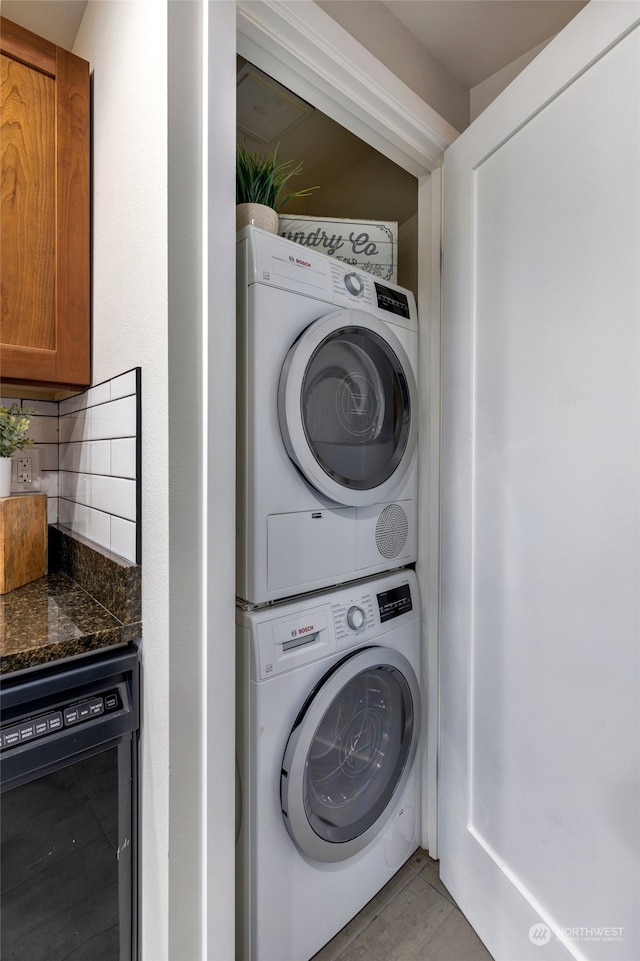 laundry room with stacked washer / dryer, light tile patterned floors, and wine cooler