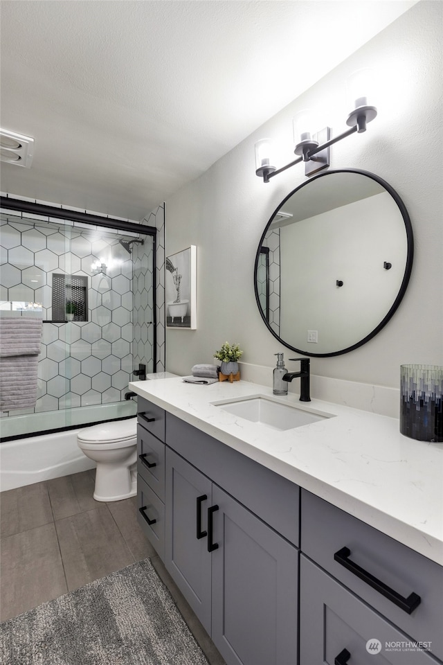 full bathroom featuring tile patterned floors, vanity, toilet, and enclosed tub / shower combo