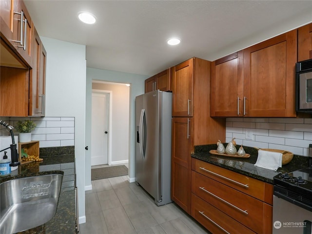 kitchen with sink, decorative backsplash, dark stone countertops, and stainless steel appliances