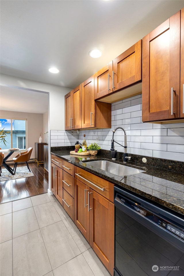 kitchen with dark stone counters, sink, decorative backsplash, black dishwasher, and light hardwood / wood-style floors