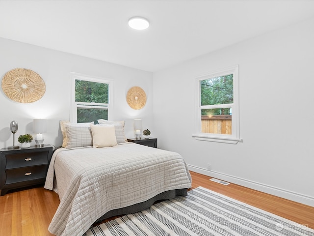 bedroom with hardwood / wood-style floors and multiple windows