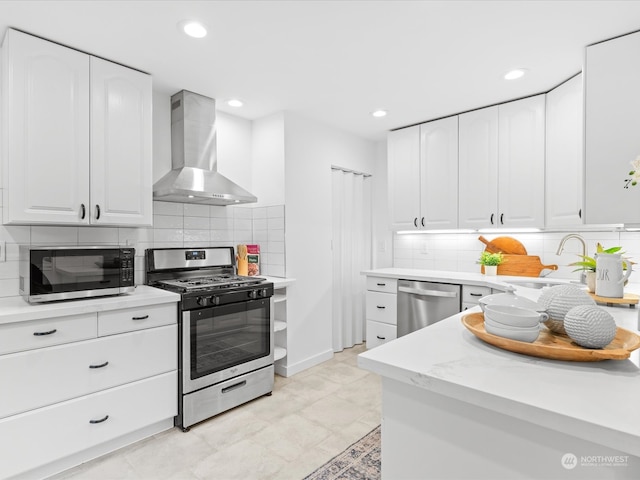 kitchen with sink, appliances with stainless steel finishes, tasteful backsplash, wall chimney exhaust hood, and white cabinets