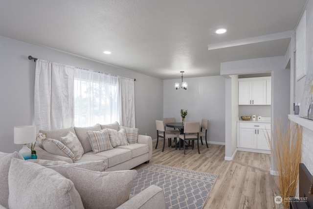 living room featuring light hardwood / wood-style flooring, a textured ceiling, and an inviting chandelier