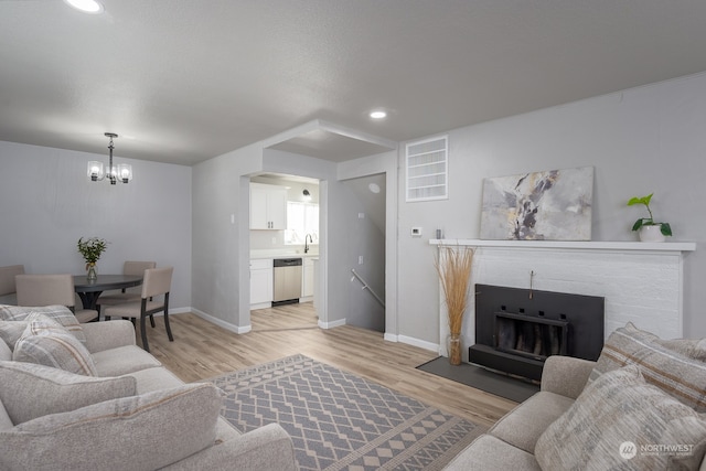 living room featuring an inviting chandelier, light wood-type flooring, and sink