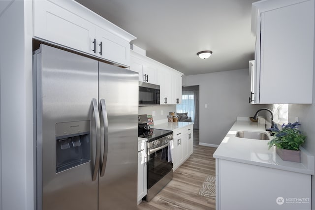 kitchen with light wood-type flooring, white cabinetry, sink, and stainless steel appliances