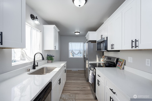 kitchen with light wood-type flooring, white cabinets, sink, and stainless steel appliances