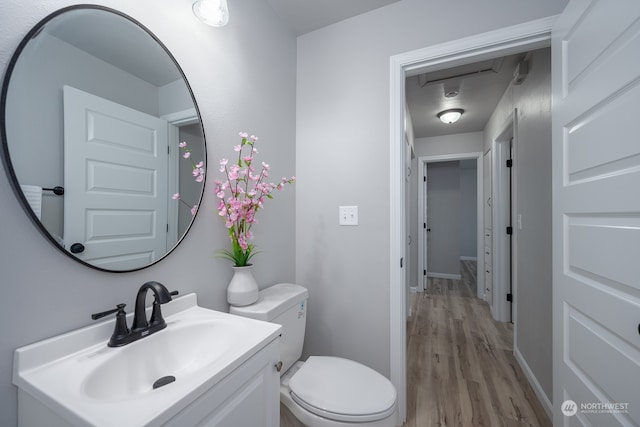 bathroom with hardwood / wood-style flooring, vanity, and toilet