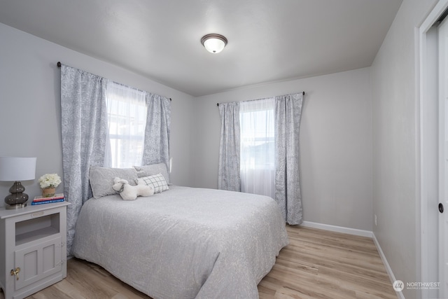 bedroom with multiple windows and light hardwood / wood-style flooring