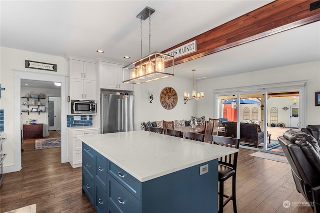 kitchen featuring stainless steel appliances, decorative light fixtures, blue cabinetry, white cabinets, and dark hardwood / wood-style flooring