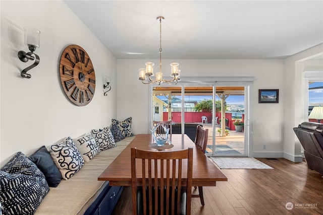 dining space with hardwood / wood-style floors, a wealth of natural light, and an inviting chandelier