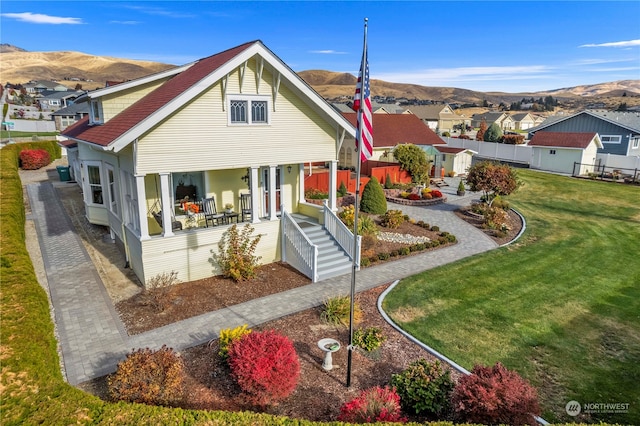 view of front of house with a front lawn, a mountain view, and covered porch