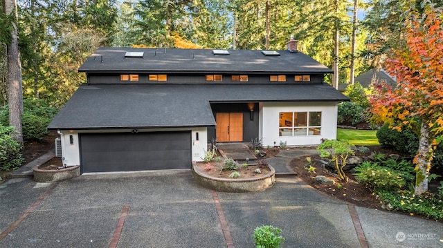 view of front of house featuring a garage, driveway, and a chimney