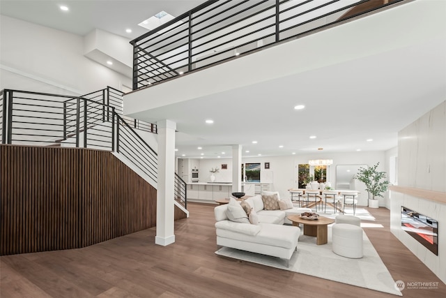 living area featuring a notable chandelier, stairway, wood finished floors, and recessed lighting