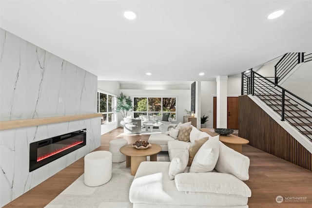 living room featuring light wood finished floors, stairway, a fireplace, and recessed lighting