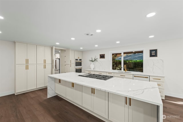 kitchen with a spacious island, white cabinets, appliances with stainless steel finishes, and light stone countertops