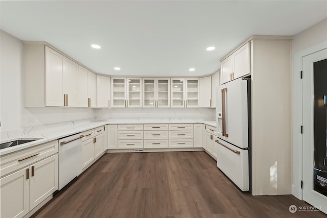 kitchen with dark wood-style flooring, glass insert cabinets, white cabinetry, light stone countertops, and white appliances