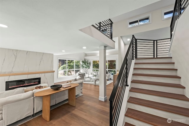 stairway with a high end fireplace, ornate columns, recessed lighting, and wood finished floors