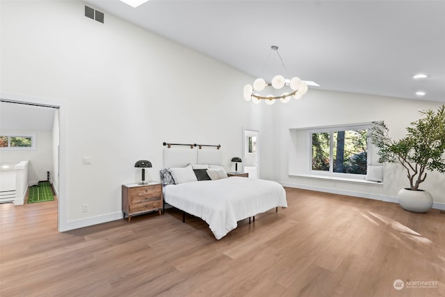 bedroom with baseboards, visible vents, a chandelier, wood finished floors, and high vaulted ceiling