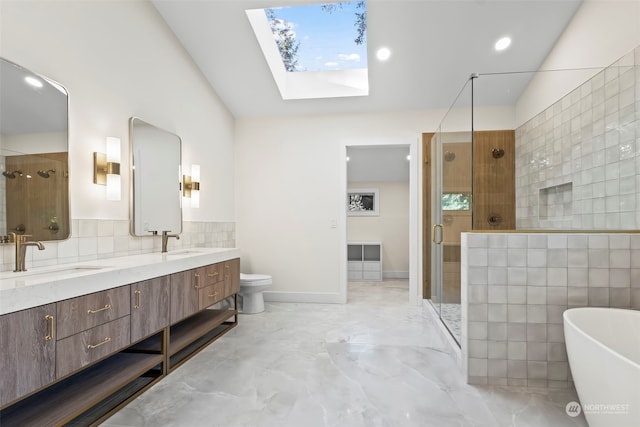 full bathroom with double vanity, a stall shower, a skylight, and a sink