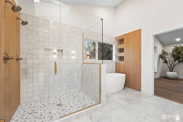 bathroom featuring a freestanding tub, a shower stall, and marble finish floor